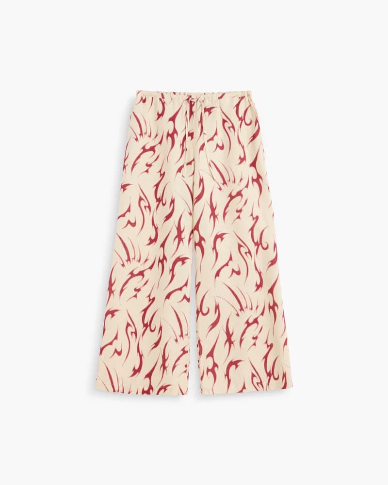 Women's off-white wide-leg linen pants with a deep red abstract flame pattern.